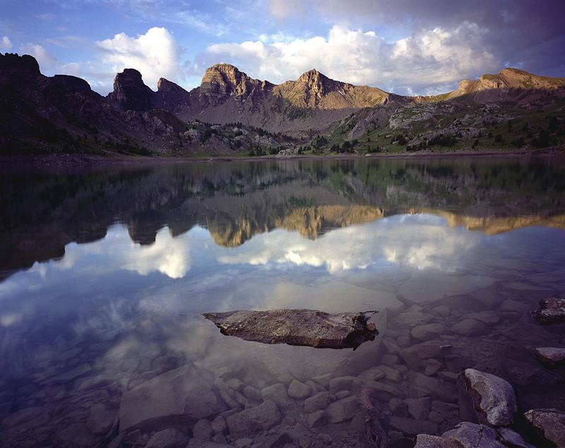 Ambiance crépusculaire et reflets sur le lac d'Allos. Au fond, les tours du lac en grès d'Annot