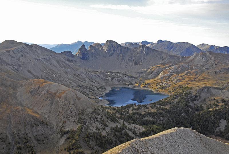 Vue large et plongeante sur le lac d'Allos et ses 2 îlots à 2228 m. Autour, les tours en grès d'Annot dont la plus haute, la Grande Tour, culmine à 2745 m