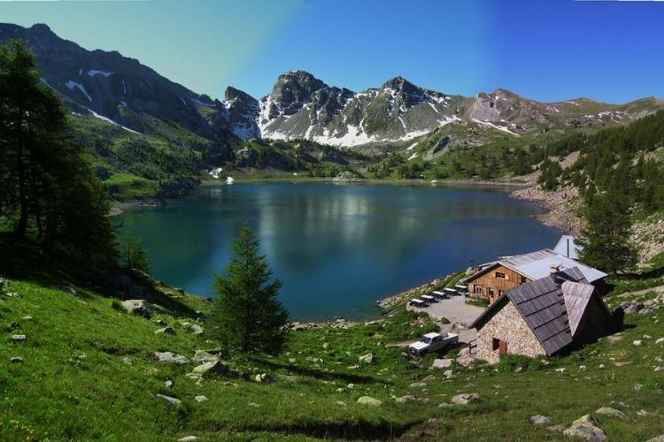 Vue large du lac d'Allos et ses montagnes en fond, ainsi que du refuge sur la droite avec sa terrasse et ses tables et chaises - Vue large du lac d'Allos et ses montagnes en fond, ainsi que du refuge sur la droite avec sa terrasse et ses tables et chaises